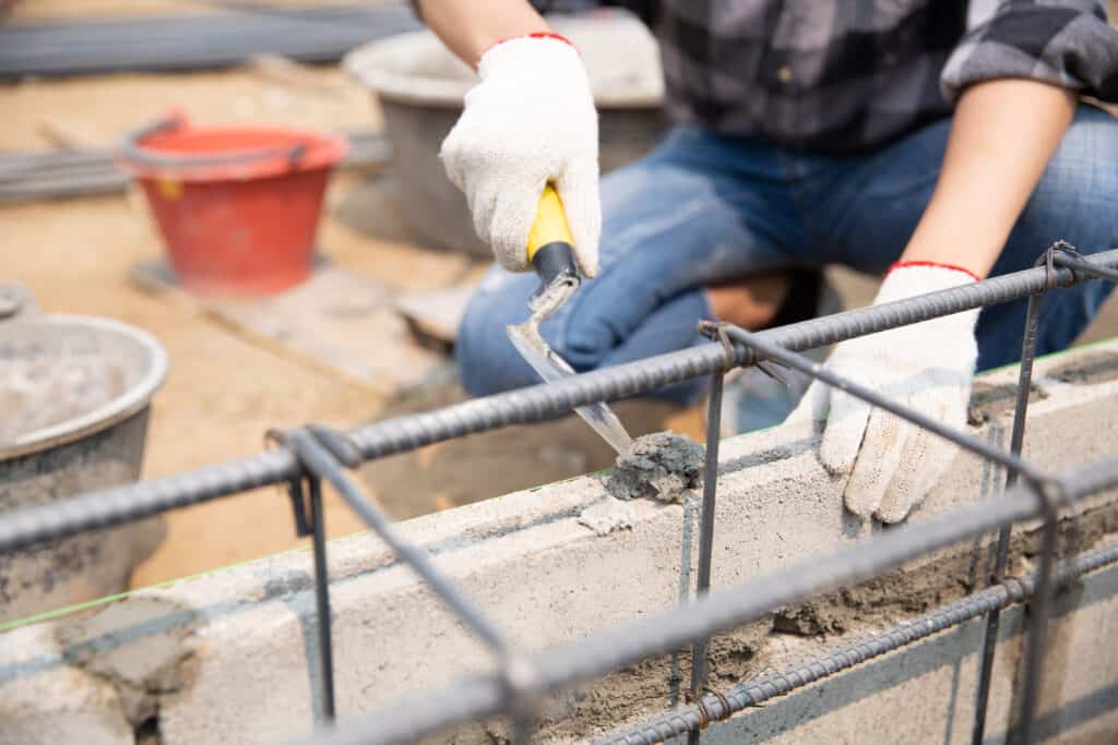 Bricklayer worker installing brick masonry on exterior wall with